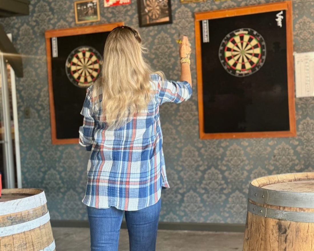 Guest throwing darts in the game area at Southern Range Brewing
