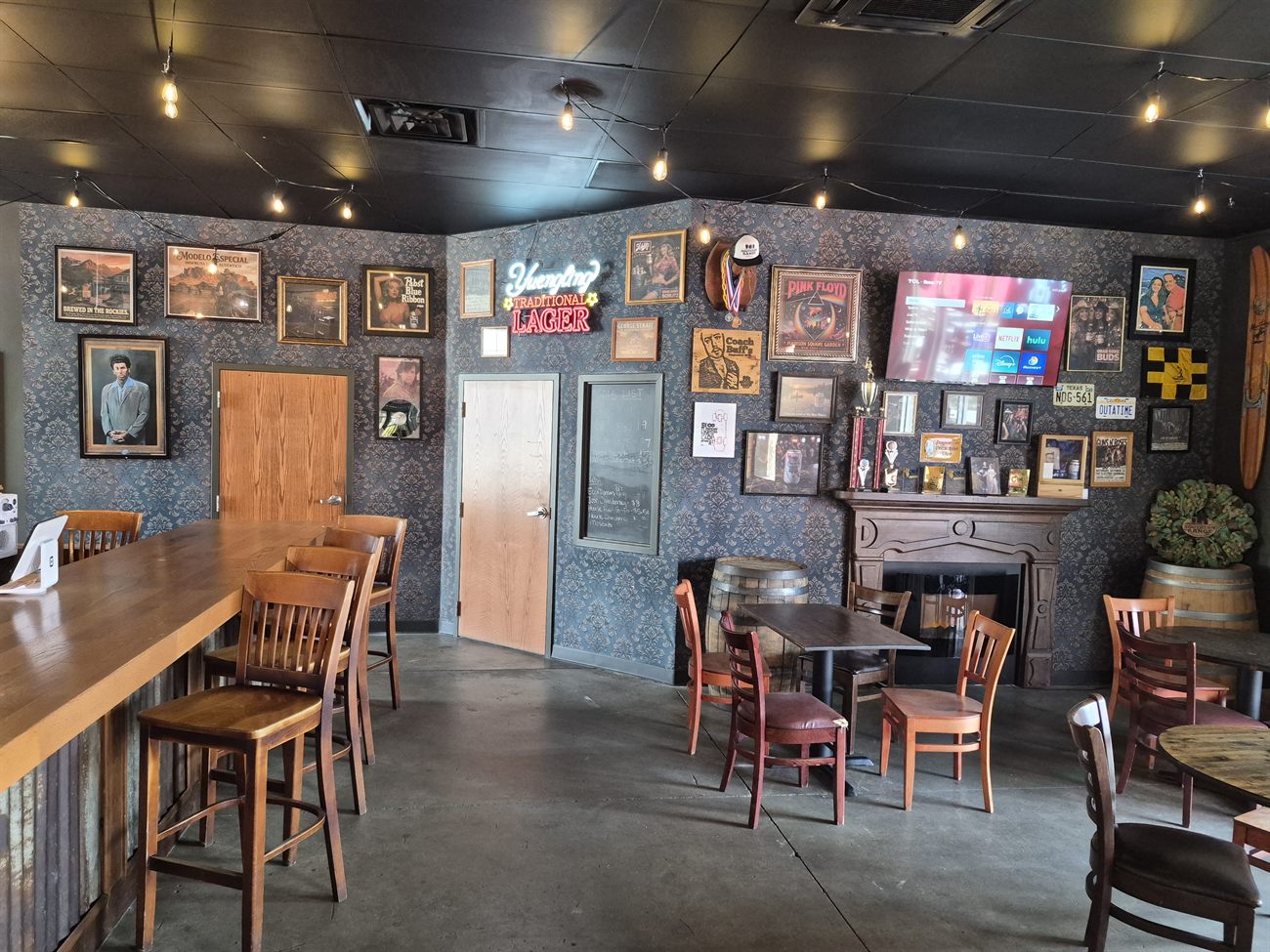 Cozy front bar with neon signs and a fireplace at Southern Range Brewing